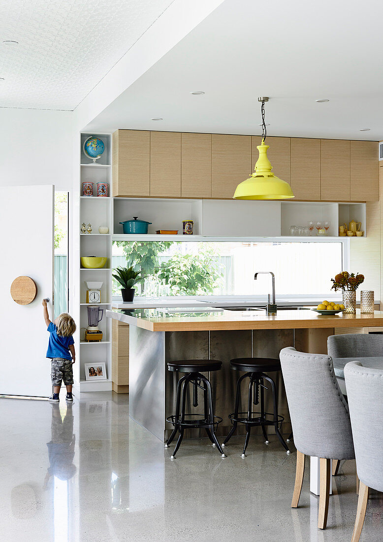 Bright, open kitchen with counter and polished concrete floor, in the back and toddler