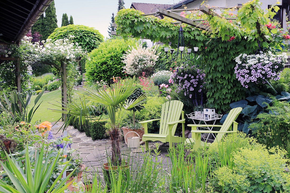 Two green deckchairs on terrace in summery garden