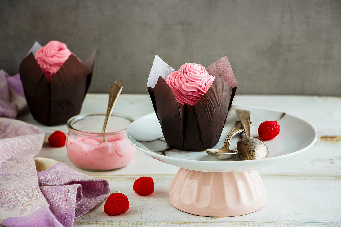 Delicious frosting cupcakes decorated with pink cream cheese and raspberry