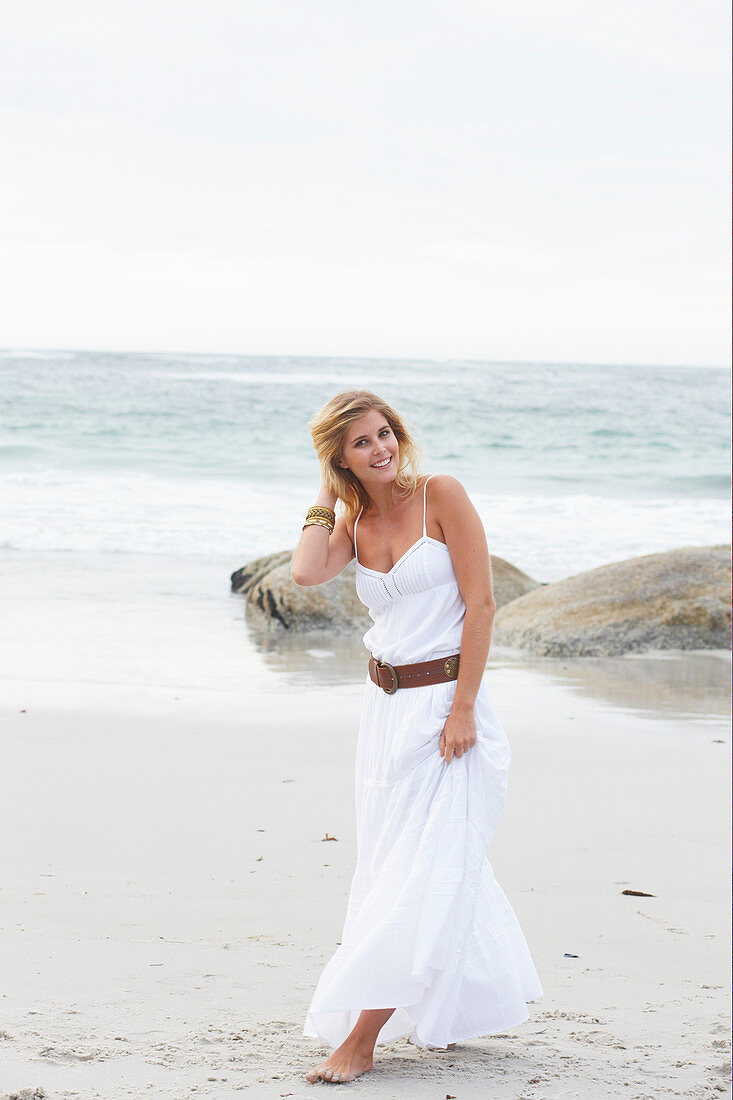 Blond Frau in weißem Sommerkleid am Meer