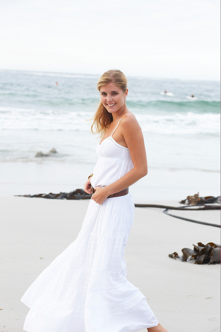 Blond Frau in weißem Sommerkleid am Meer