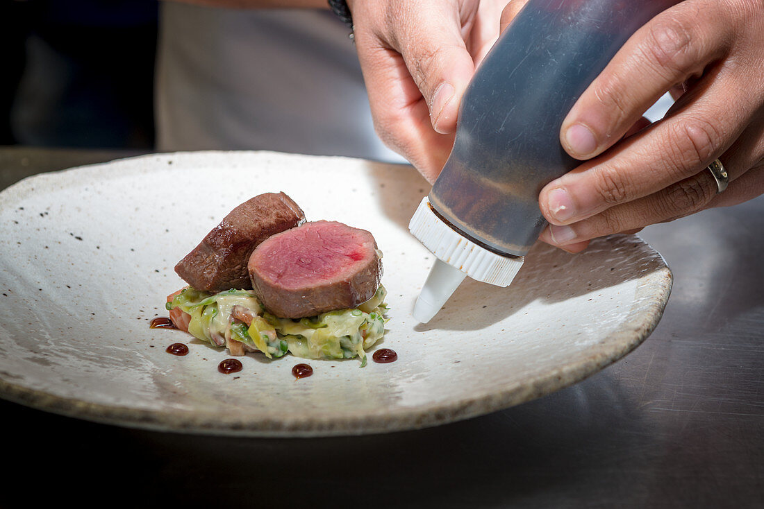 A lamb fillet dish being plated
