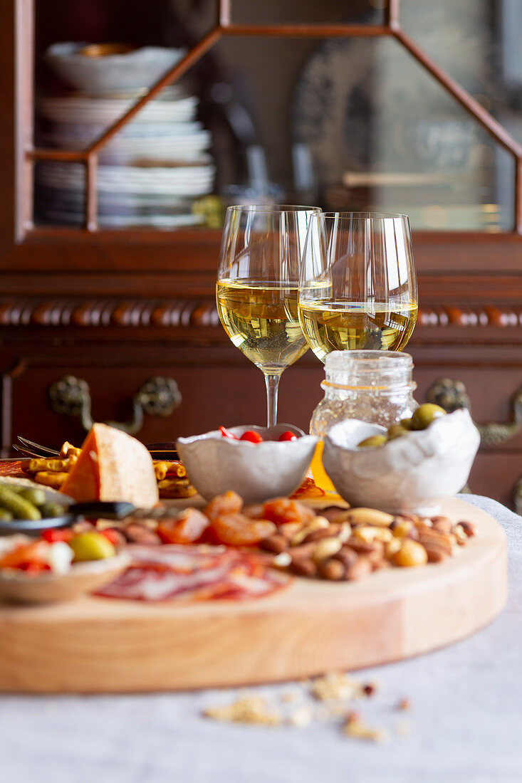 Chacuterie-Platte mit Wurst, Käse, Knabbereien und Weißwein