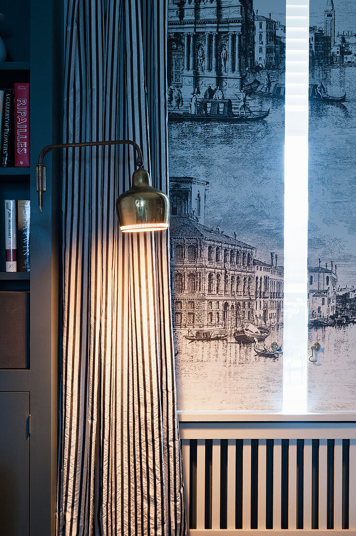 Wall-mounted lamp in front of striped curtain and window with shutters