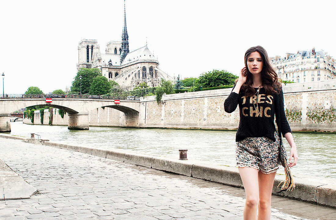 Junge brünette Frau im Shirt und Rock am Seineufer neben der Kathedrale Notre-Dame