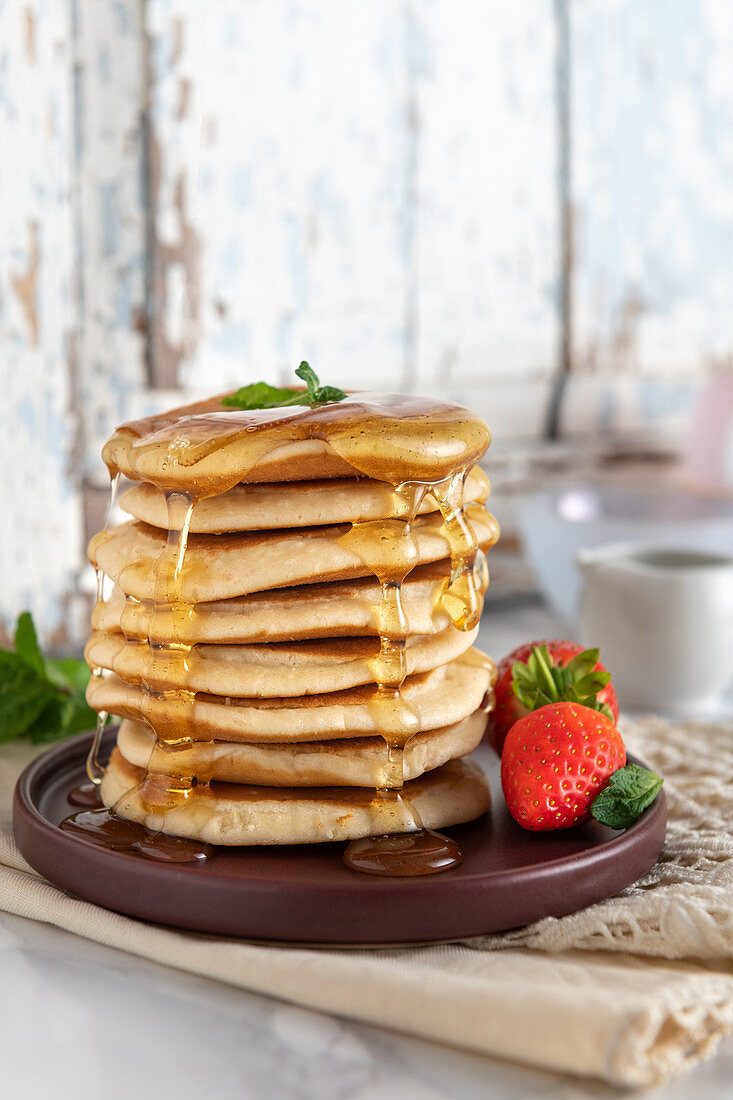 Ein Stapel Pancakes mit Honig und Erdbeeren
