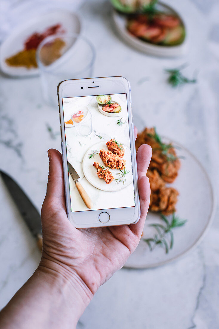 Handyfoto von frittiertem Hähnchen mit Gewürzen und Tomaten