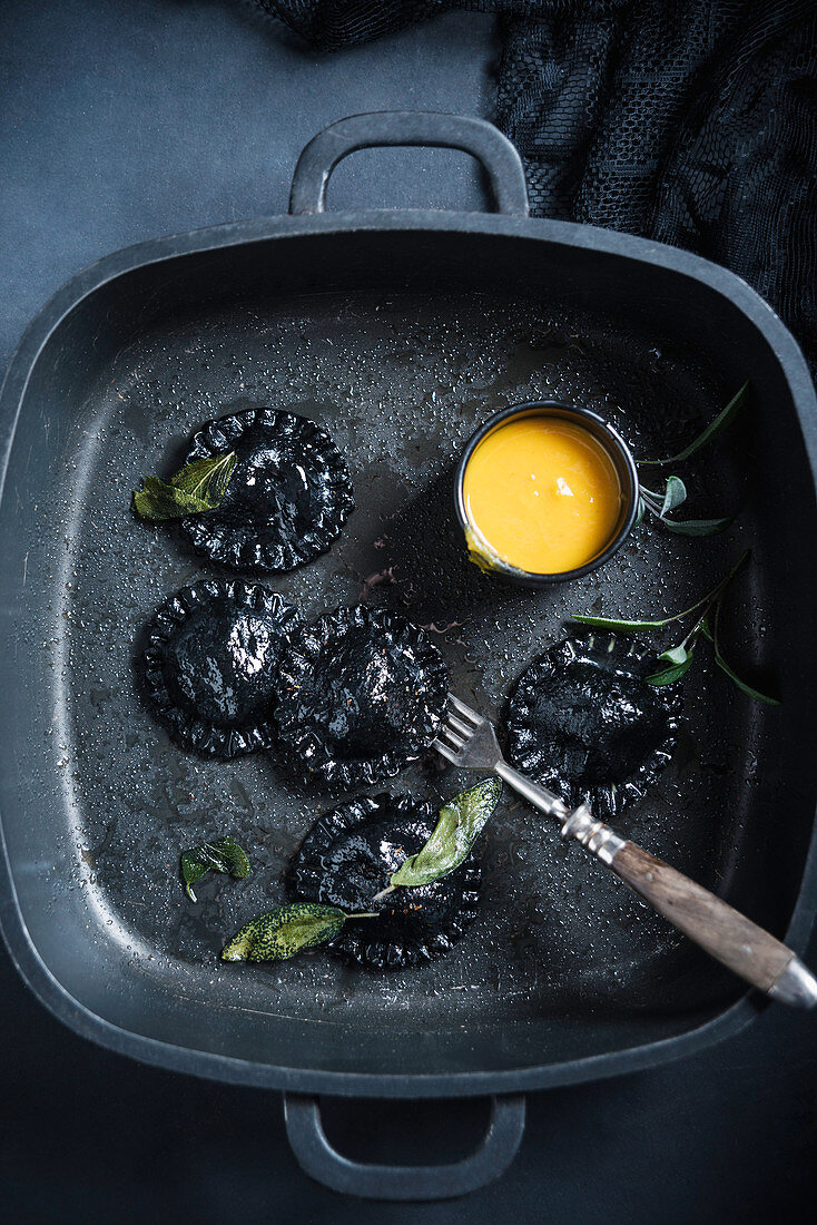 Vegane schwarze Ravioli (gefärbt mit Aktivkohle) in Salbeibutter, gefüllt mit Kürbispüree