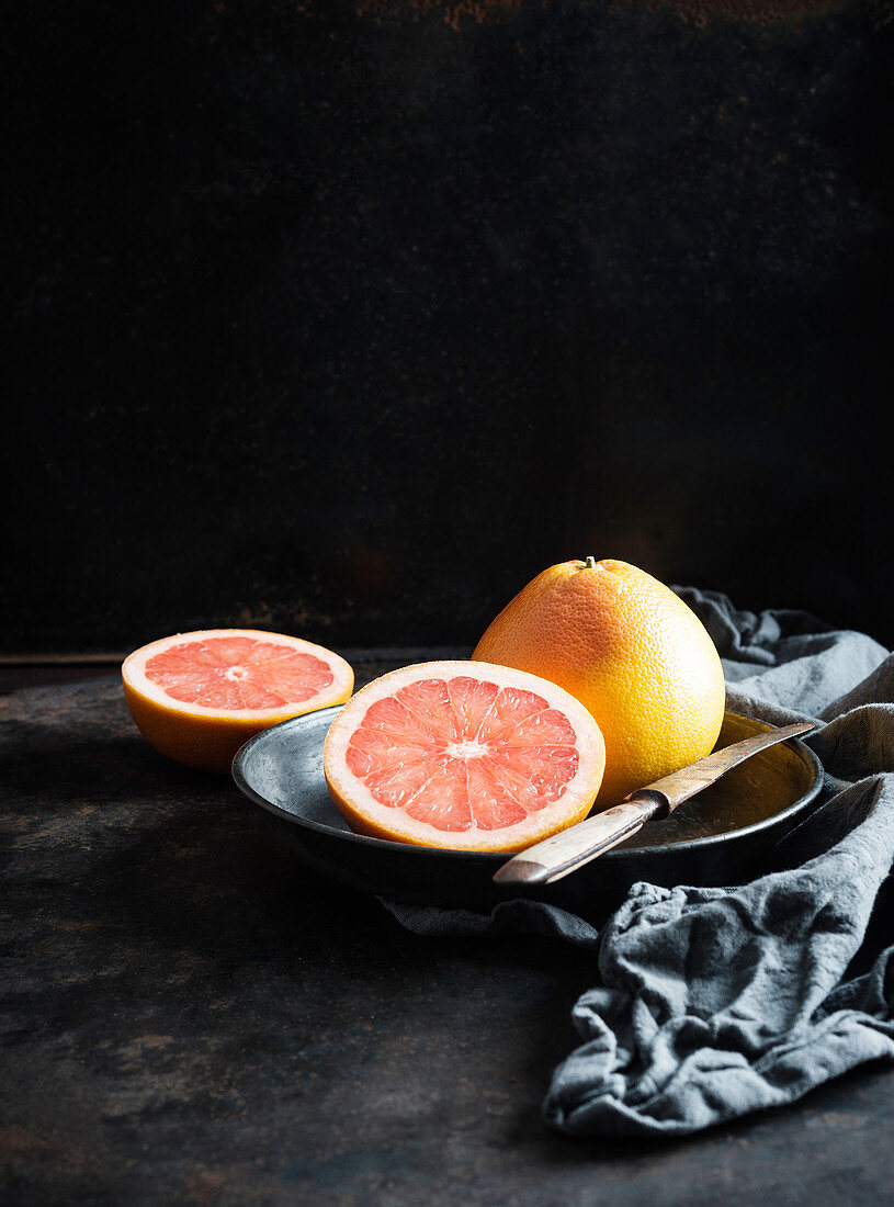 Two pink grapefruit (citrus paradisi) on a metal plate