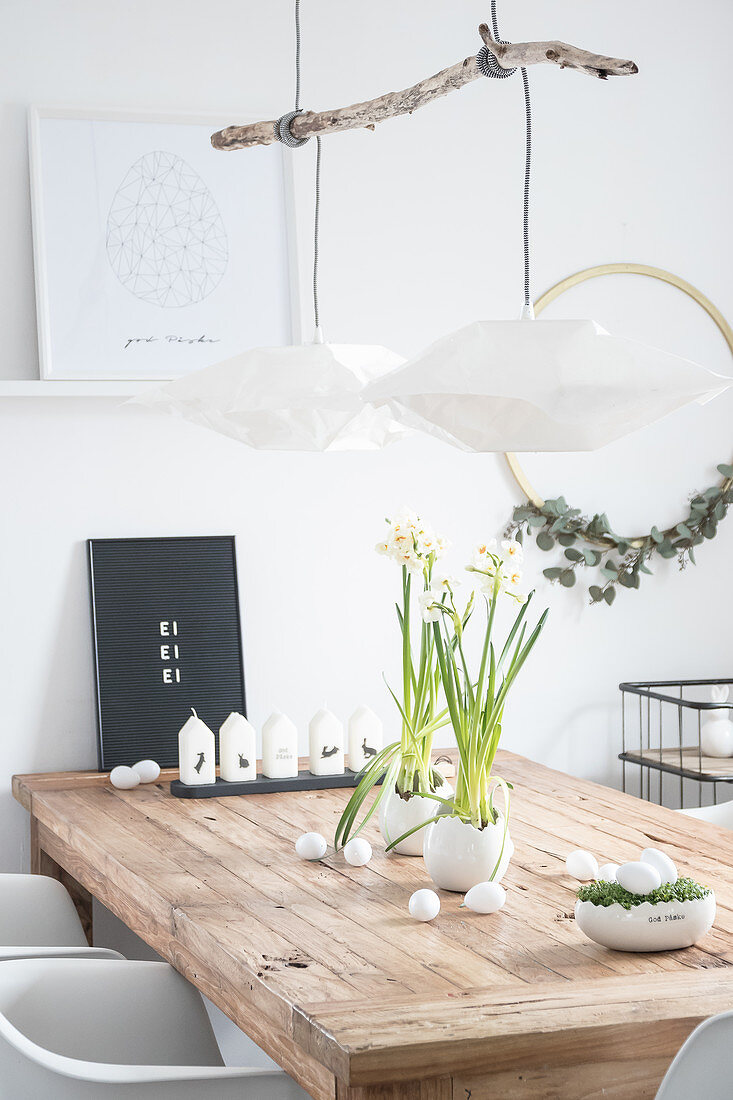 Holztisch mit Osterdekoration: Kerzen, Narzissen und Kresse-Nest mit weißen Eiern