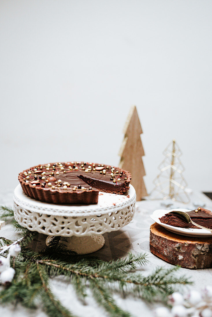 Schokoladentarte auf Kuchenständer und weihnachtlich dekoriertem Tisch
