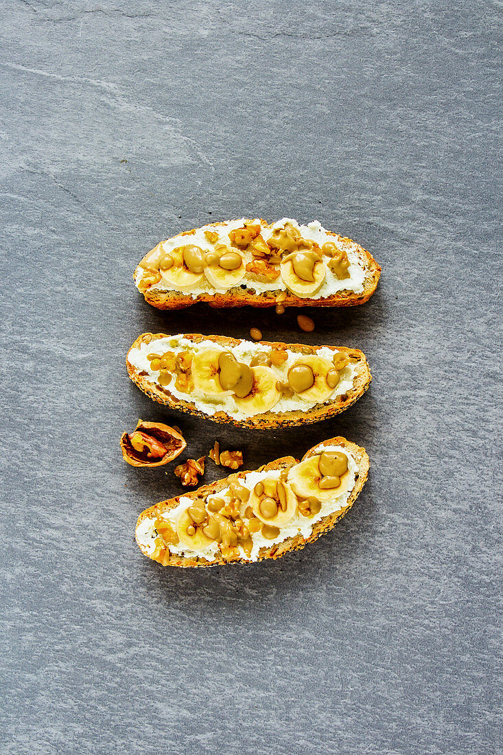 Three ricotta cheese toasts with banana and nuts