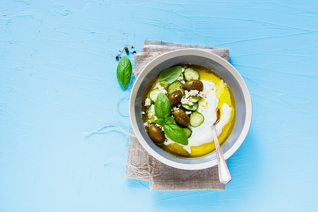 Joghurt mit Oliven, Feta, Gurken, Olivenöl und Basilikum