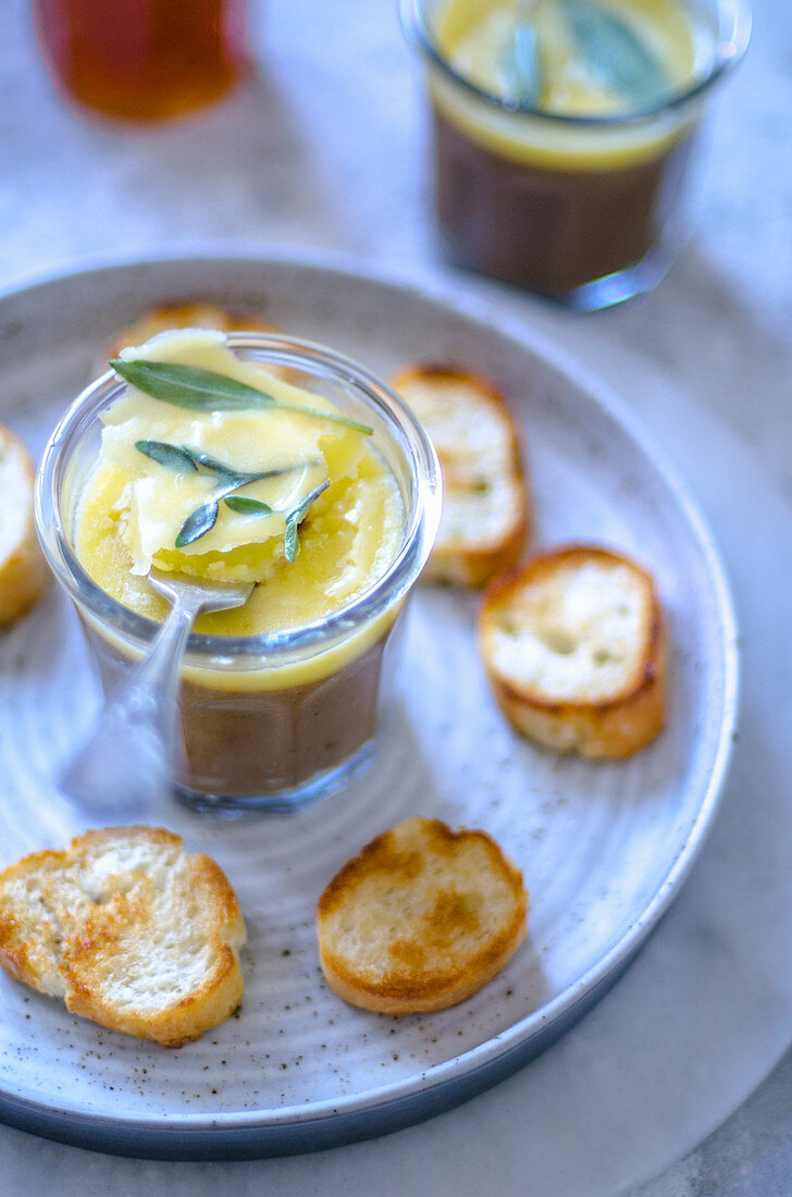 Homemade pate with butter and sage leaves with croutons on a gray plate