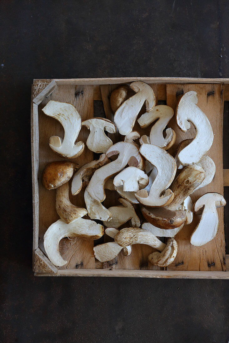 Halved porcini mushrooms in a wooden crate