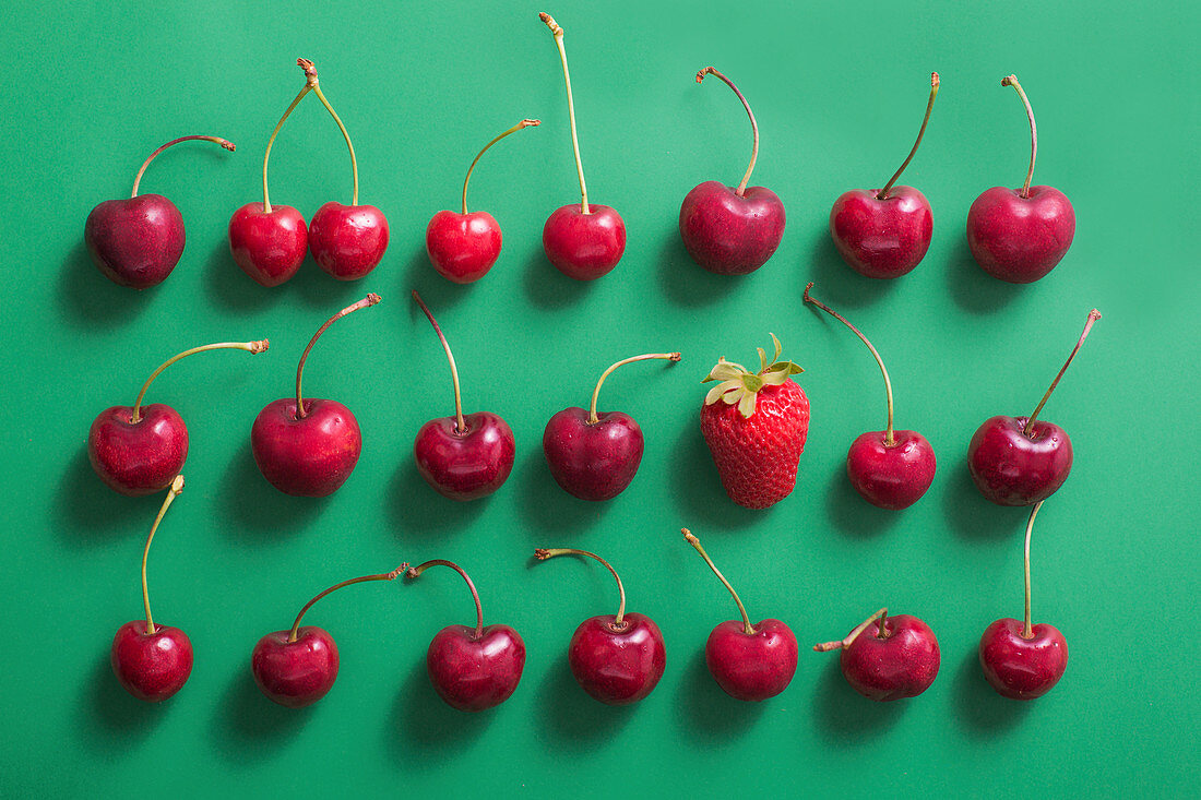 An arrangement of cherries and one strawberry