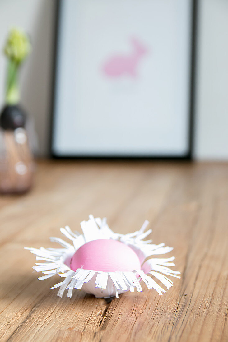 Easter egg in handmade paper nest on wooden surface