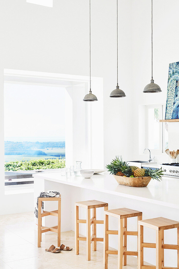 Kitchen counter with wooden bar hoppers and pendant lights in the background window with sea view