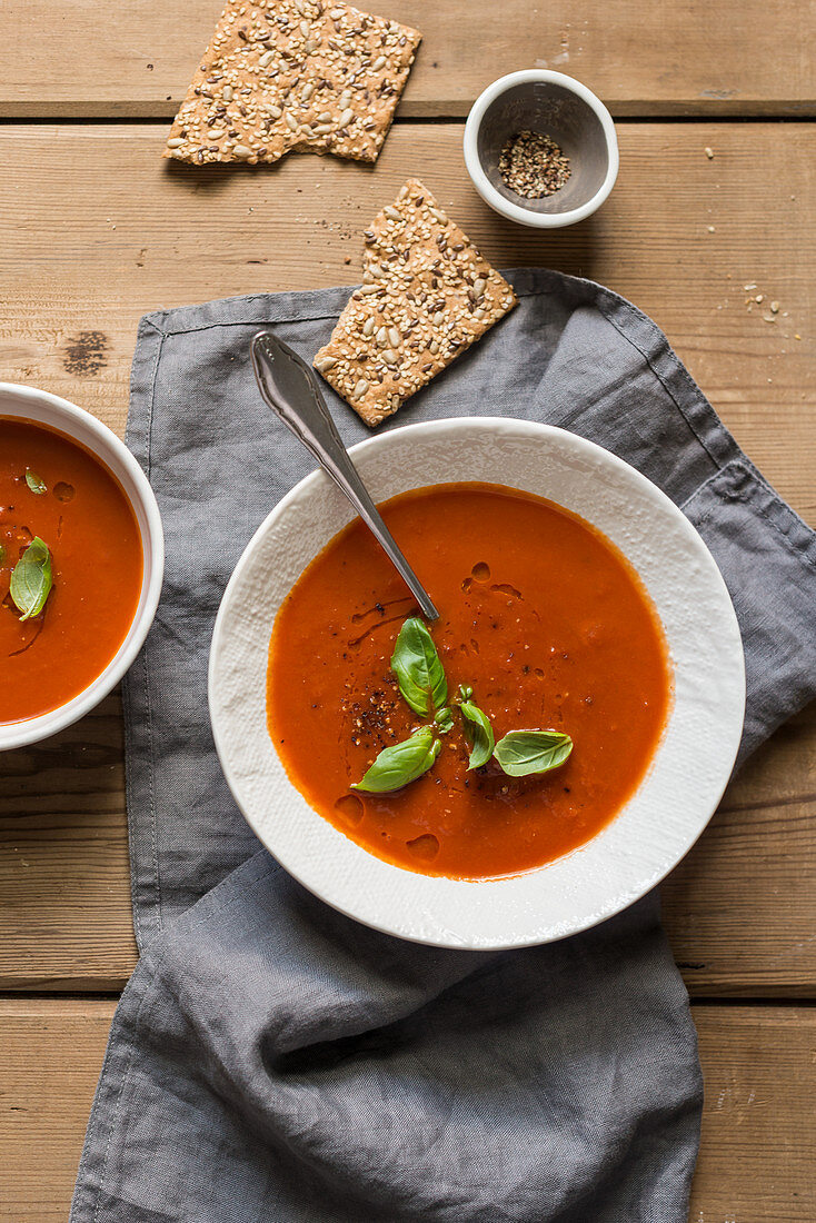 Tomato soup with fresh basil on a wooden table