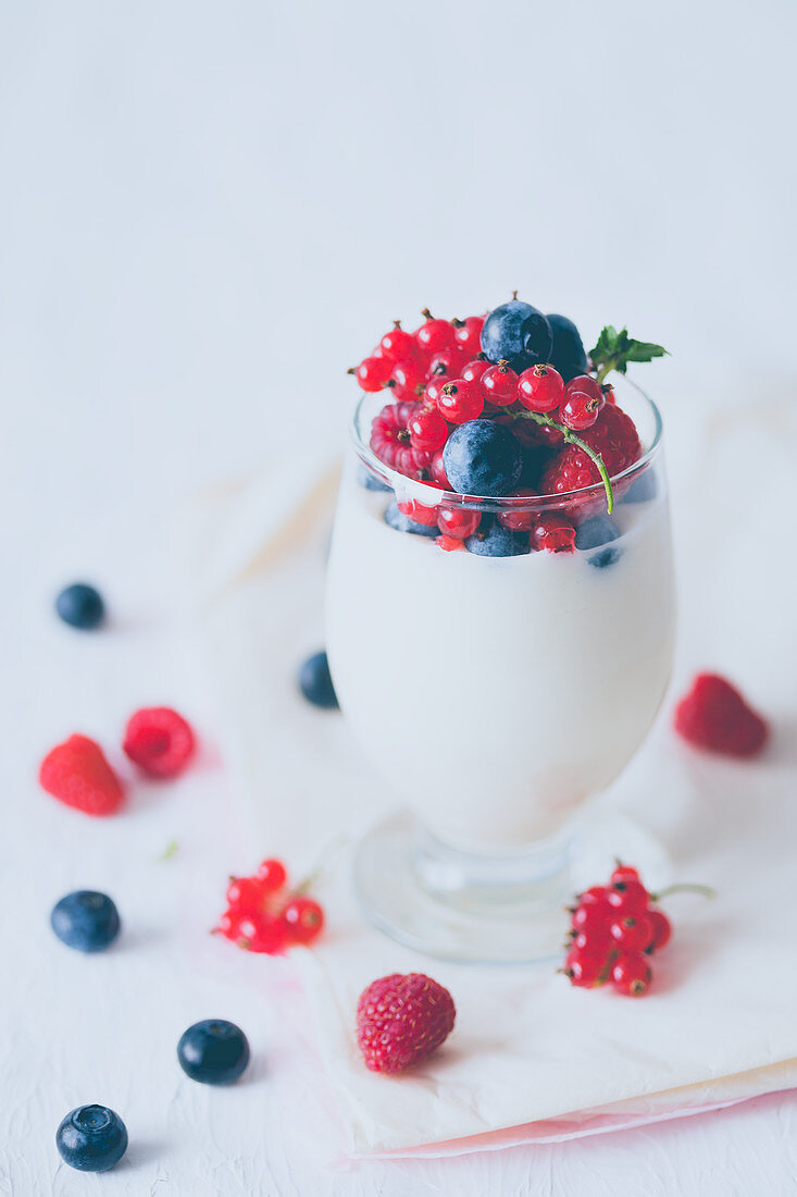 Coconut and white chocolate mousse with berries in a glass