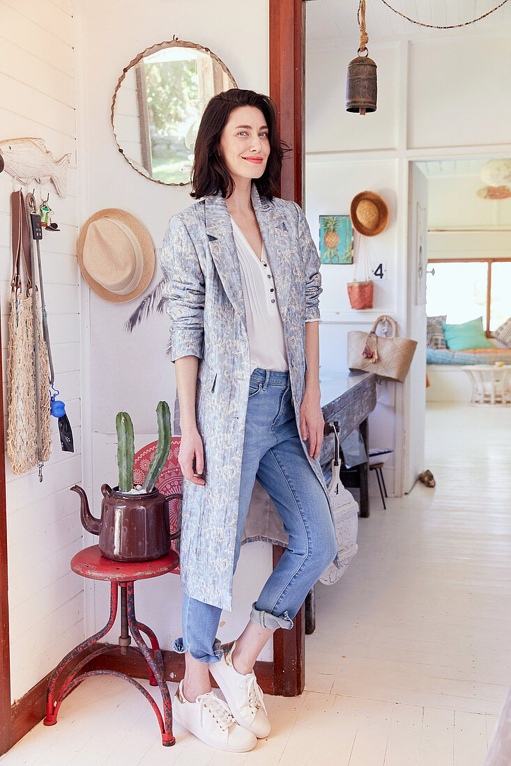A brunette woman wearing blue jeans, a shirt and a long cardigan