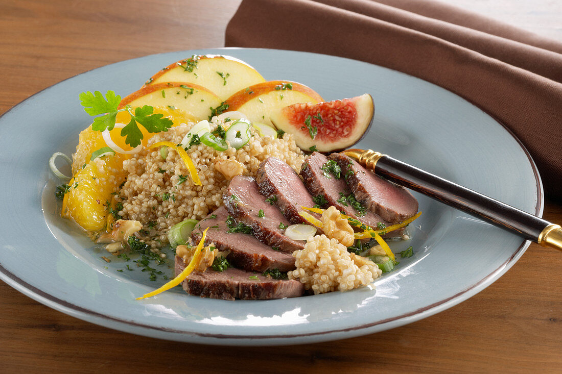 Wintery quinoa salad with venison fillet, orange, apple, and figs on a plate