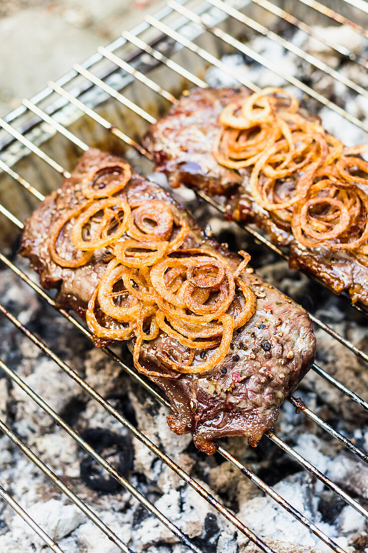 Beef steaks with onions on a grill rack