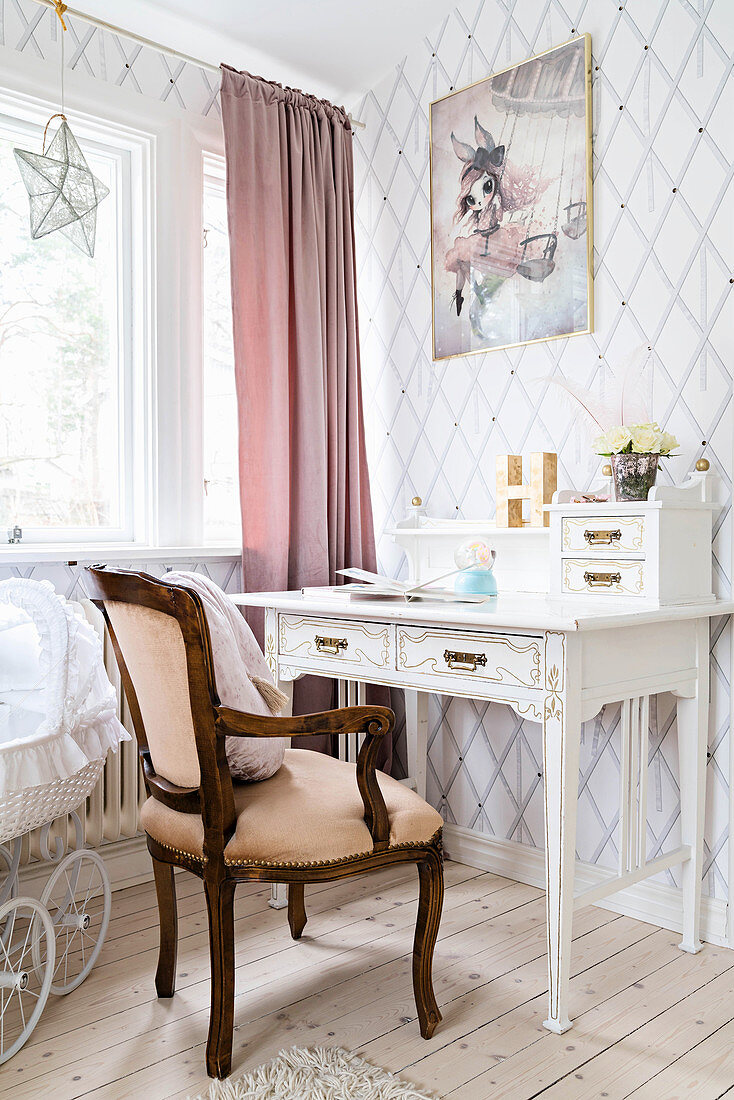 Vintage desk and antique armchair in bright room with diamond-patterned wallpaper