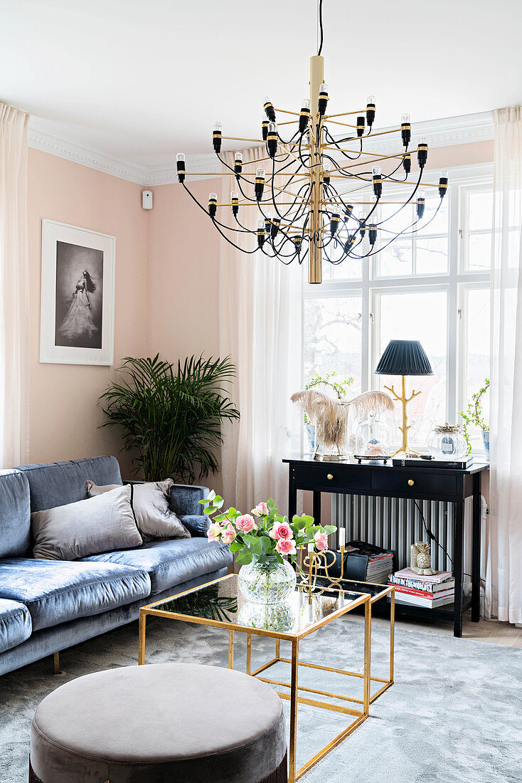Dark velvet sofa, black console table, delicate coffee table with glass top and pouffe in pale pink living room