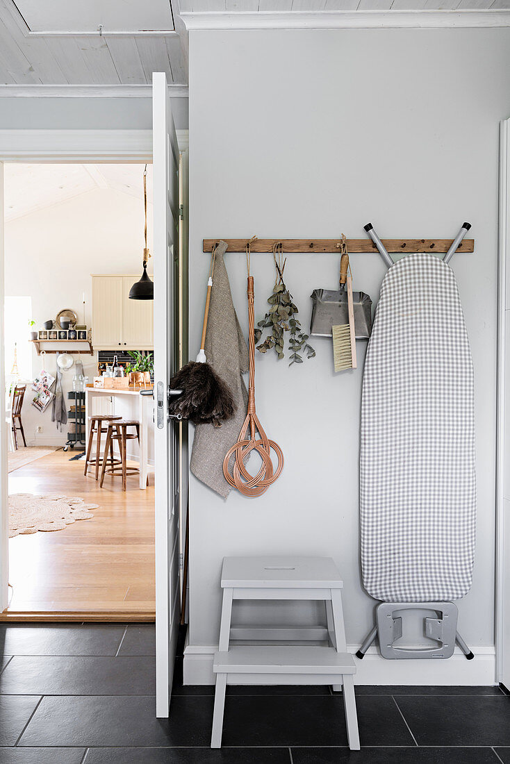 Cleaning utensils hung from cat pegs on wall behind door