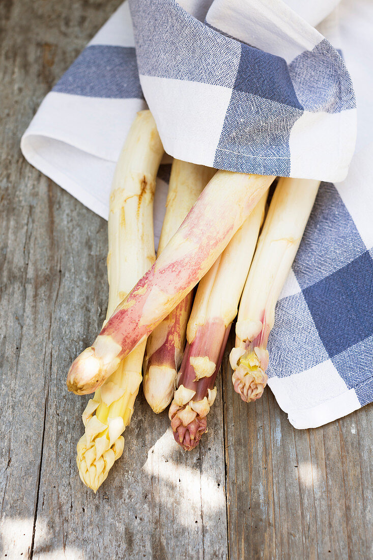 White asparagus, wrapped in a linen cloth, on a wooden background