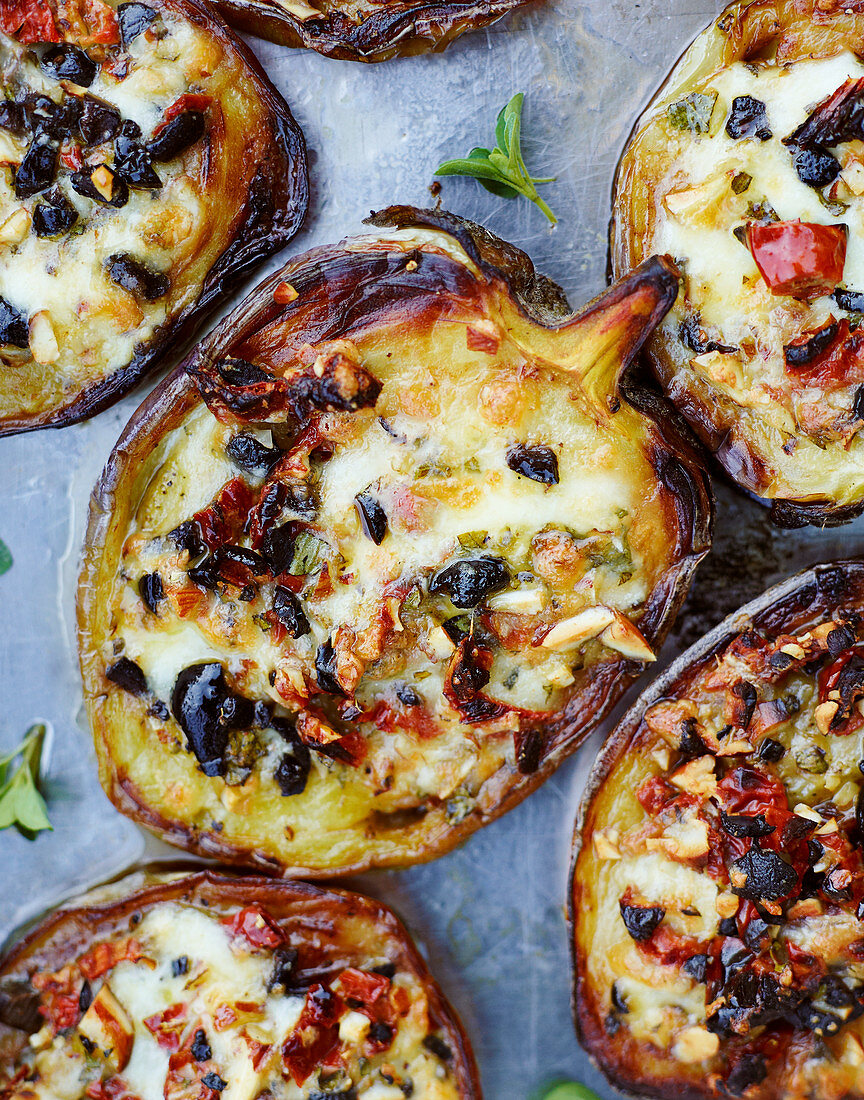 Oven-baked aubergines with olives, almonds and cheese