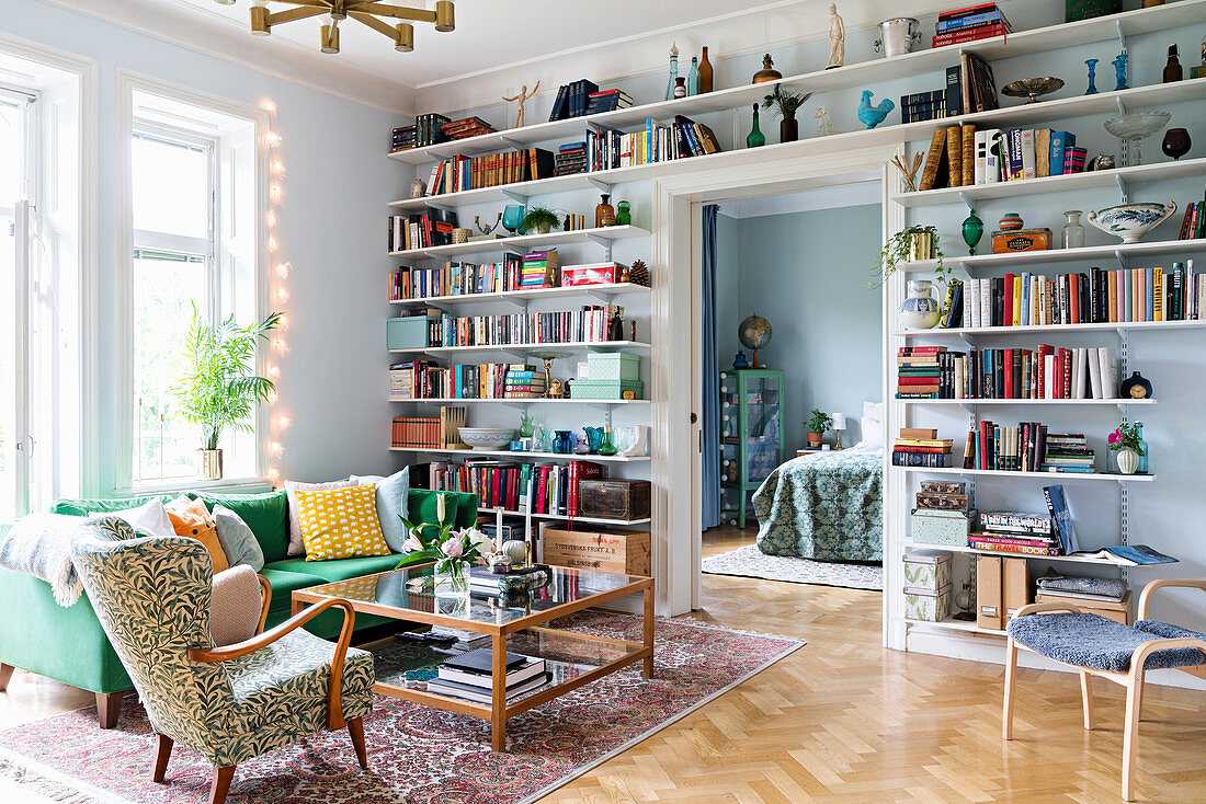 Wohnzimmer mit deckenhohen offenen Wandregalen für Bücher und Deko