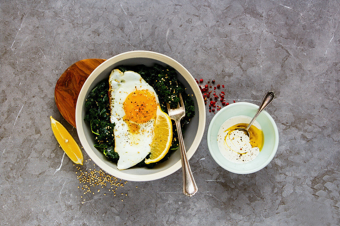 Fresh vegetarian lunch bowl with fried egg, kale and sesame seed