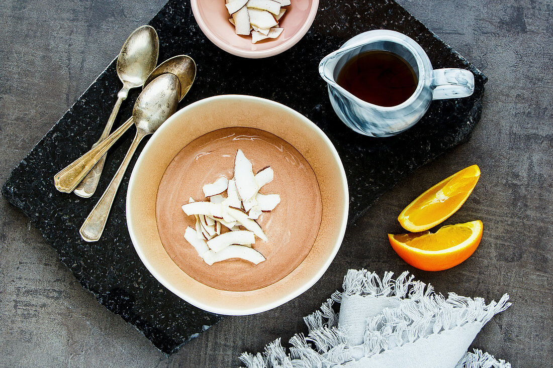 Schokoladenjoghurt-Bowl mit Ahornsirup, Orange und Kokoschips (Aufsicht)