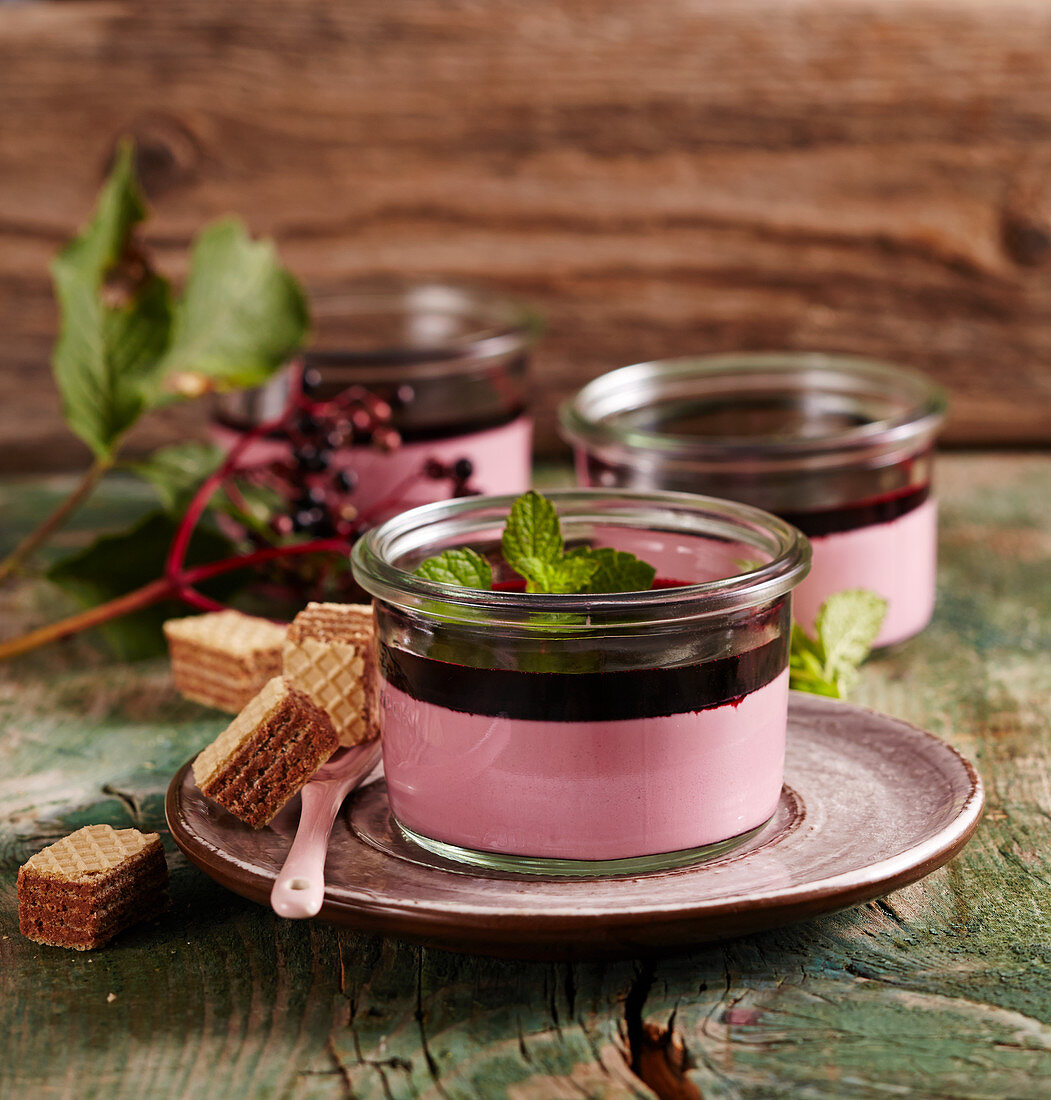 Elderberry panna cotta in glasses with mint, elderflower syrup and wafers