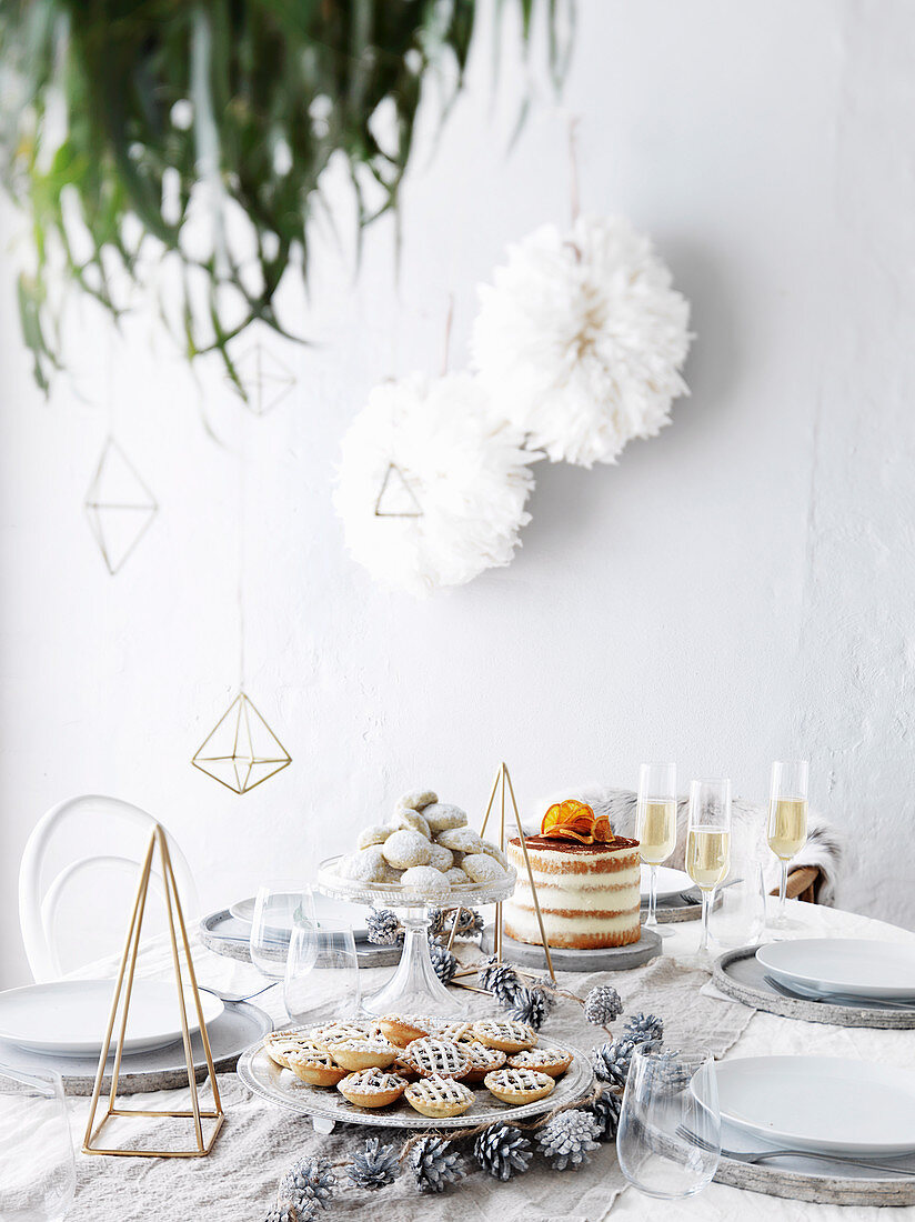 Gedeckter Weihnachtstisch mit Kuchen, Plätzchen und Sekt
