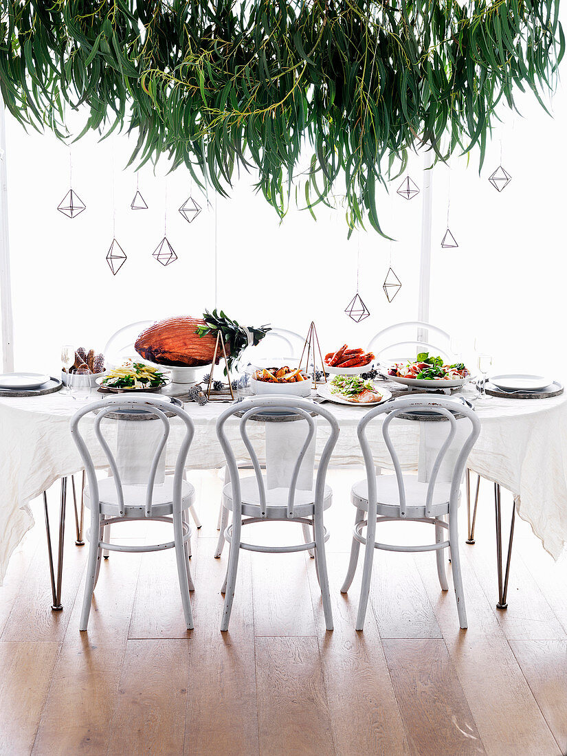 Weihnachtlich gedeckter Tisch mit Schinkenbraten und Beilagen