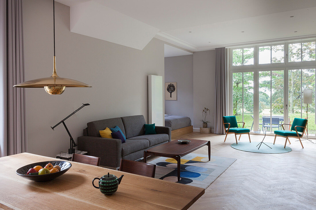 View across dining table to couch and two chairs in front of terrace doors in background