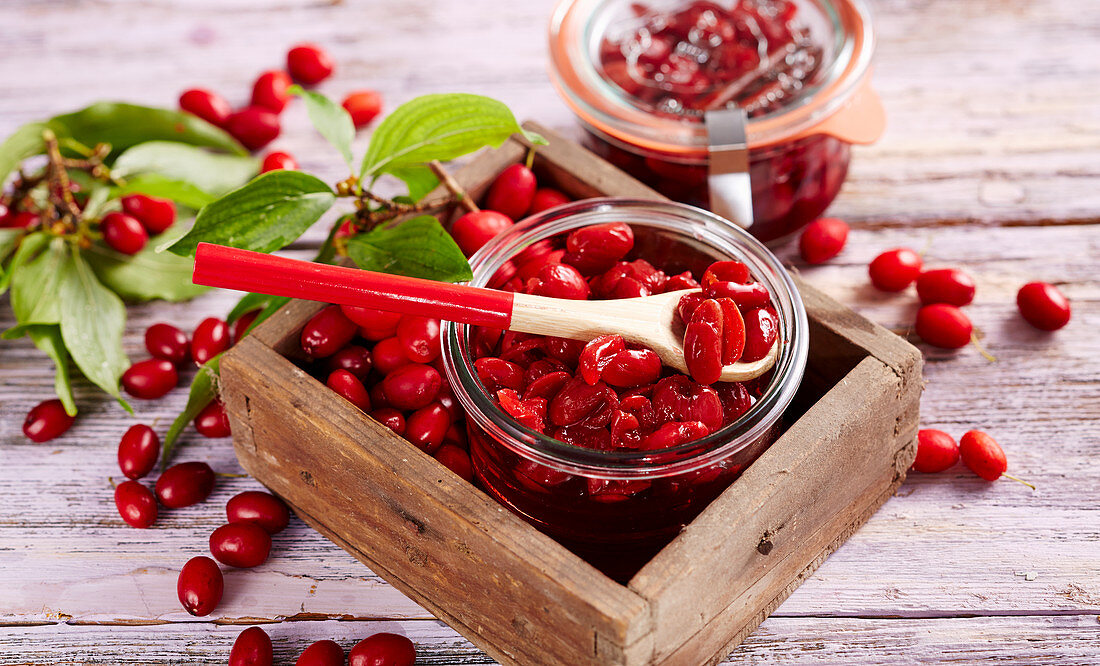 Homemade cornelian cherry compote in a glass on a wooden background