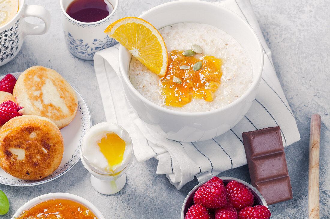 Healthy breakfast with porridge, oatmeal, pancakes, lots of berries and snacks