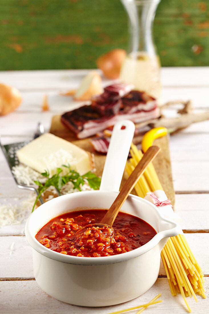 Sauce Amatriciana mit Speck, Käse, Nudeln und Wein auf Tisch