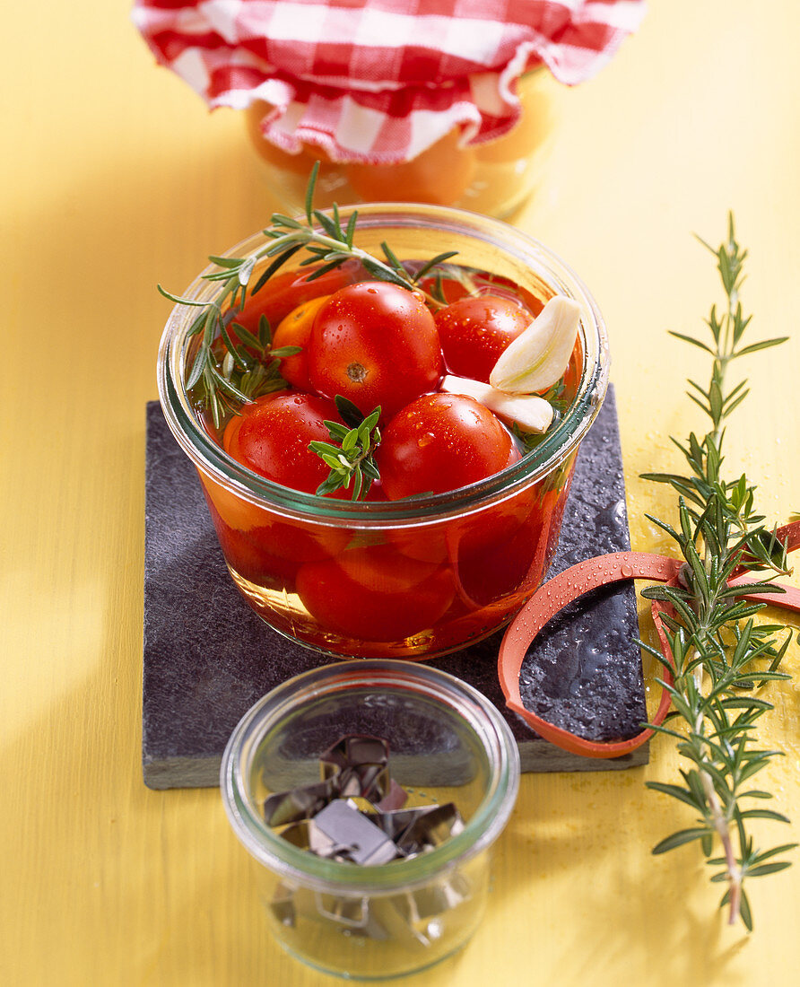 Pickled cherry tomatoes in vinegar with fresh herbs and garlic