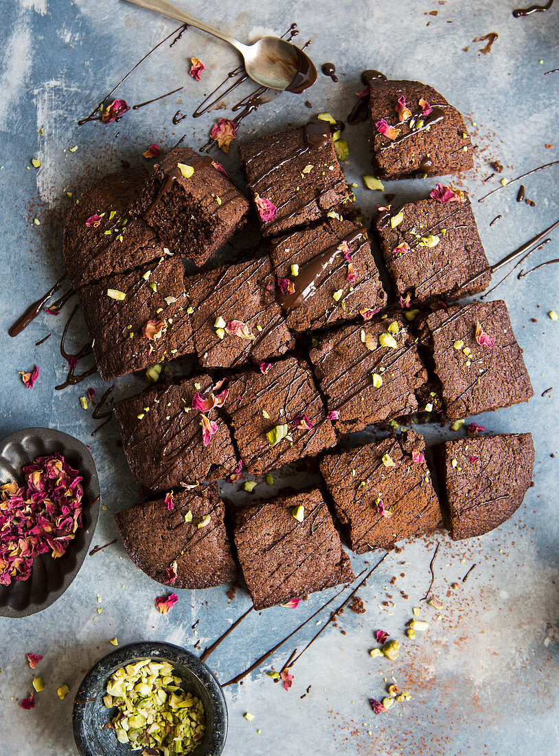 Chocolate brownies drizzeled in melted chocolate and topped with pistachio nuts and dried rose petals