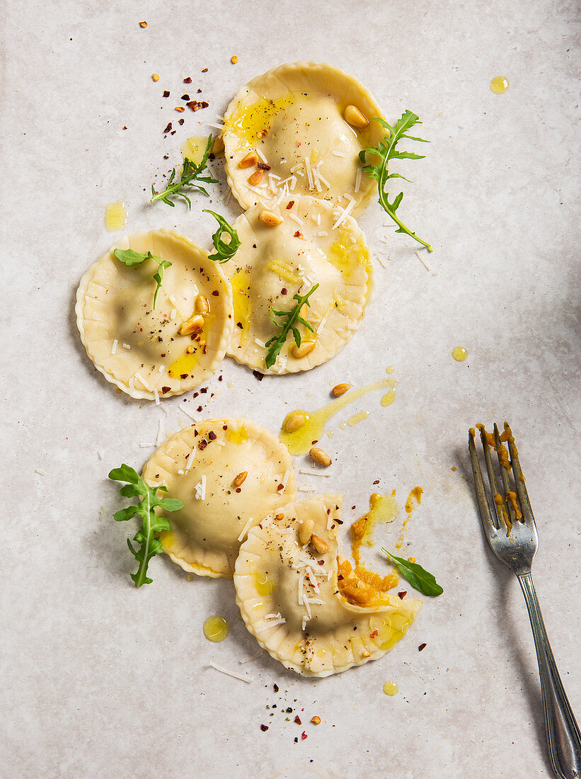 Homemade pumpkin ravioli tortelloni parcels topped with pine nuts, olive oil, rocket and chilli