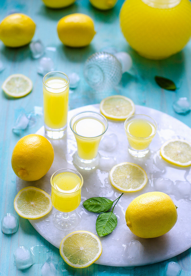 Hausgemachter Limoncello in Gläsern, Zitronen und Zitronenscheiben