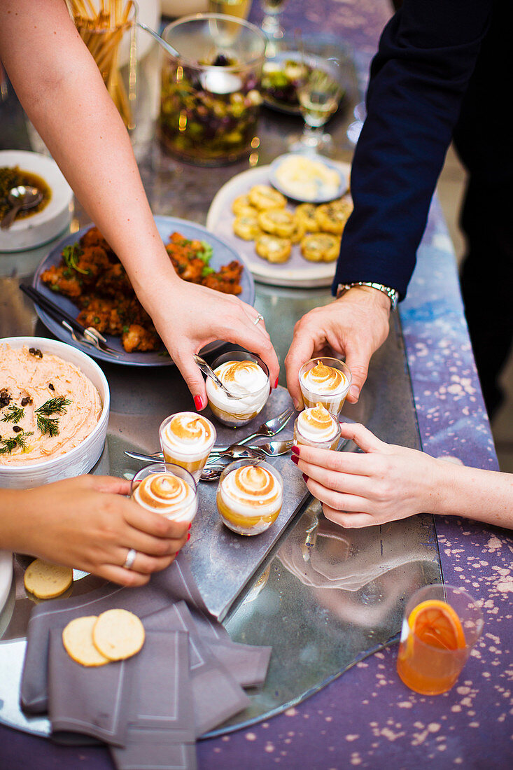 Personen greifen nach Lemon Meringue Pie Shots am festlichen Buffet