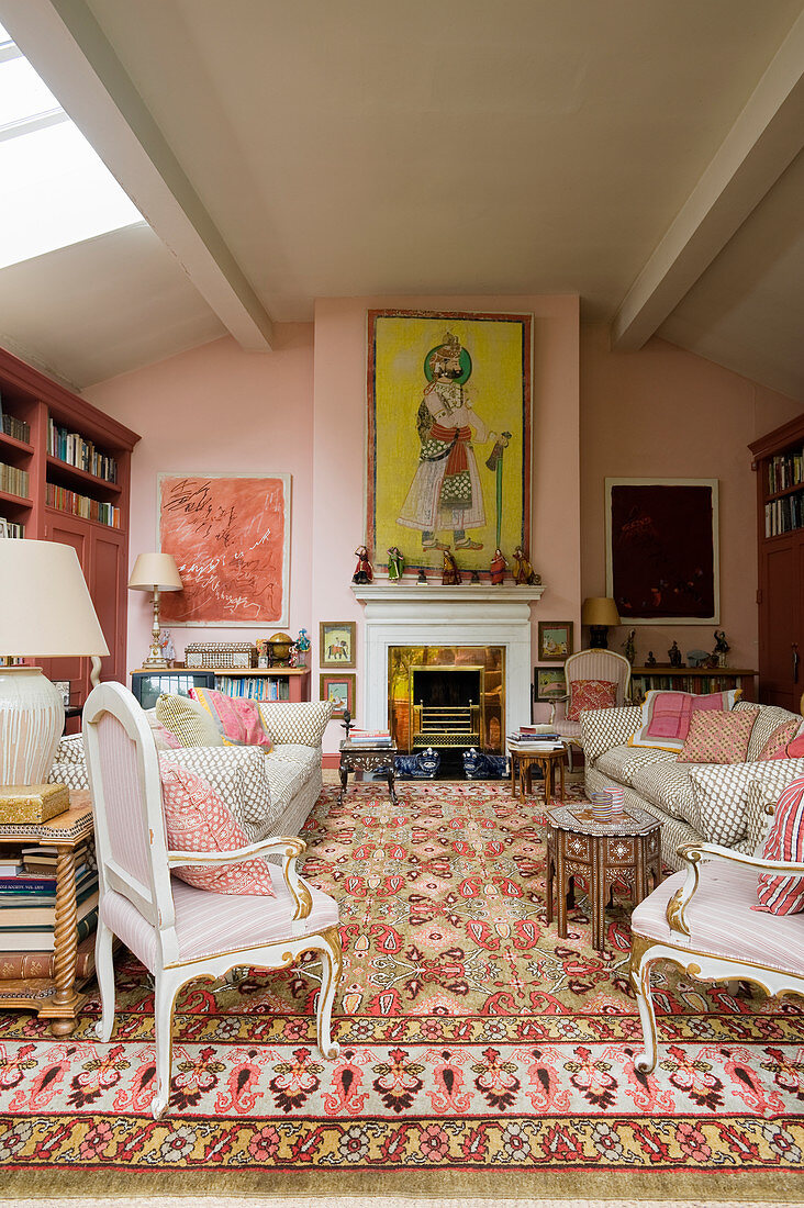 Antique armchairs and sofa in front of fireplace in living room in shades of pink