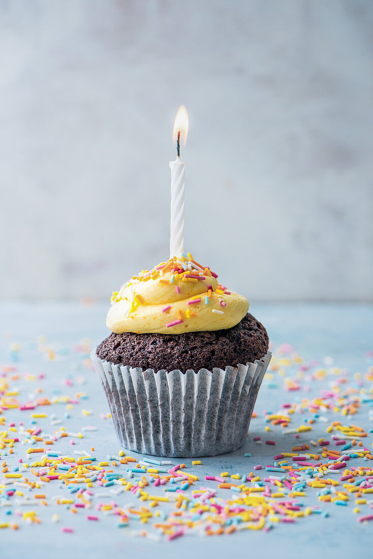 Cupcake mit bunten Zuckerstreuseln und Kerze