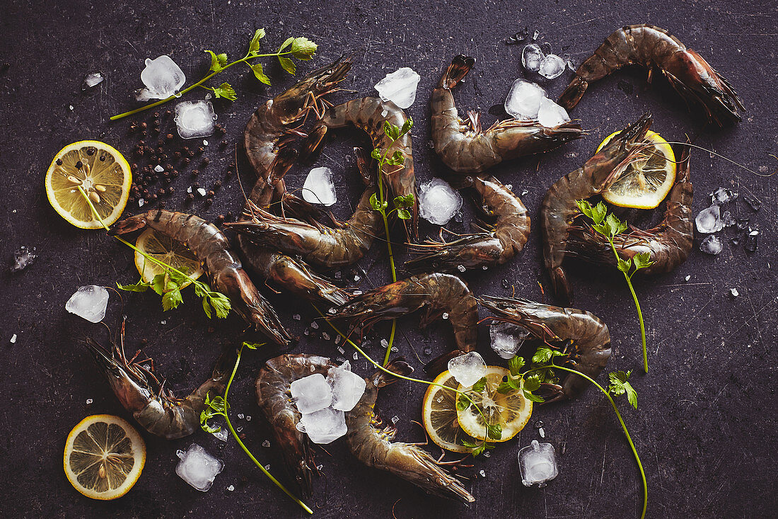 Frische Tiger Prawns und Zitronenscheiben auf dunkler Tischplatte